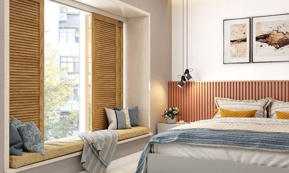 A window designed with seating and cushions and a bed in front for a home interior design for 3bhk flat