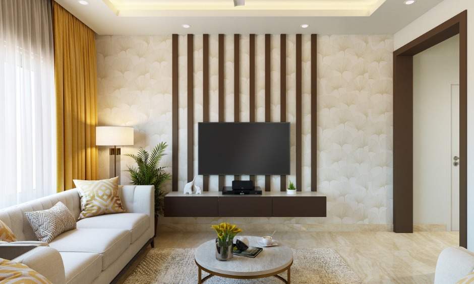 A living room in 1bhk interior features a wall-mounted tv unit with wooden panelling to highlight the wall
